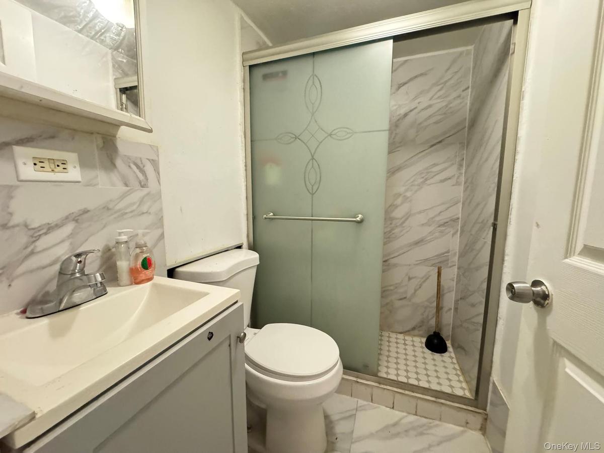 Bathroom featuring a marble finish shower, vanity, and marble finish floors