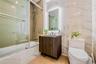 Full bath with enclosed tub / shower combo, vanity, tile walls, and light tile patterned flooring