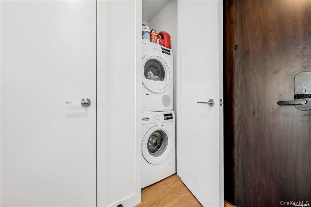 Laundry area with light wood-style flooring and stacked washer / drying machine
