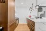 Kitchen featuring a peninsula, light stone countertops, light wood-type flooring, decorative light fixtures, and modern cabinets