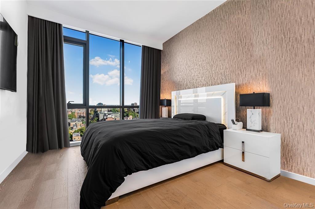 Bedroom featuring wallpapered walls, expansive windows, and light wood-style floors