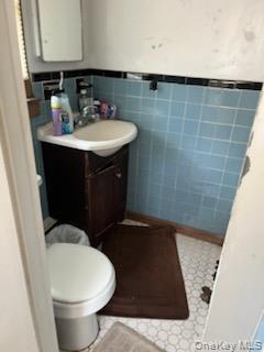 Bathroom featuring tile walls, vanity, and wainscoting