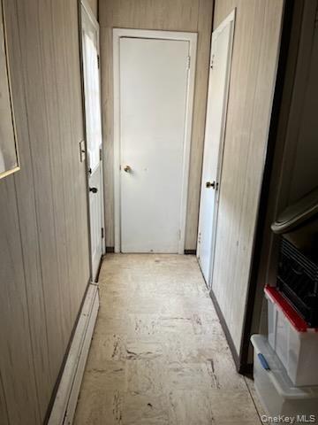 Hall featuring wood walls and a baseboard radiator