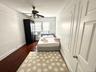 Bedroom featuring dark wood-style floors, a ceiling fan, and a decorative wall
