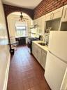 Kitchen with freestanding refrigerator, stainless steel gas range oven, light stone countertops, a ceiling fan, and under cabinet range hood