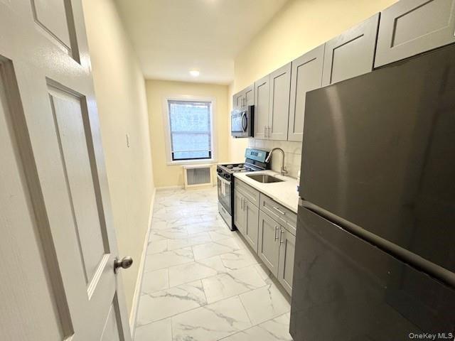 Kitchen with appliances with stainless steel finishes, gray cabinets, light marble finish flooring, light stone counters, and recessed lighting