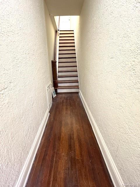 Hall with a textured wall, dark wood finished floors, and stairway