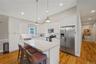 Kitchen featuring stainless steel appliances, lofted ceiling, a kitchen island, white cabinetry, and a kitchen breakfast bar