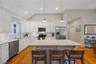 Kitchen with a breakfast bar area, vaulted ceiling, stainless steel appliances, white cabinets, and decorative backsplash