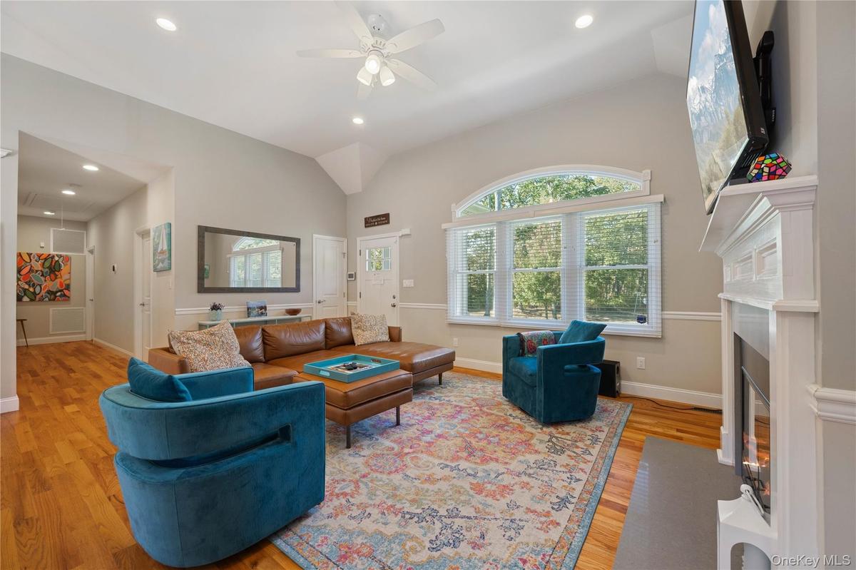 Living room featuring light wood finished floors, vaulted ceiling, a fireplace with flush hearth, recessed lighting, and ceiling fan
