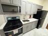 Kitchen with stainless steel appliances, gray cabinets, light marble finish flooring, and decorative backsplash