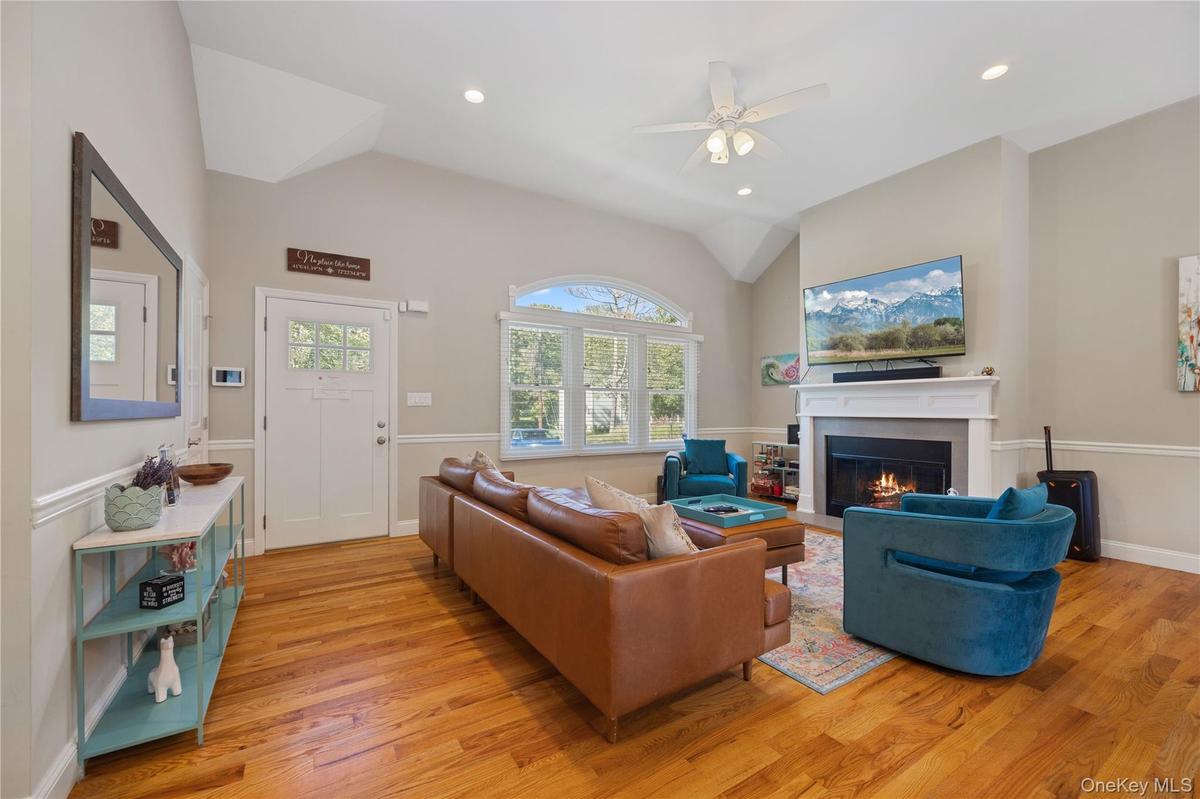 Living area featuring a glass covered fireplace, vaulted ceiling, light wood-style flooring, ceiling fan, and recessed lighting