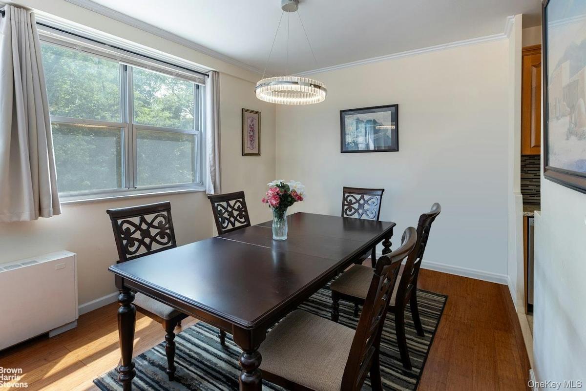 Dining area featuring light wood-style floors, radiator heating unit, baseboards, and ornamental molding