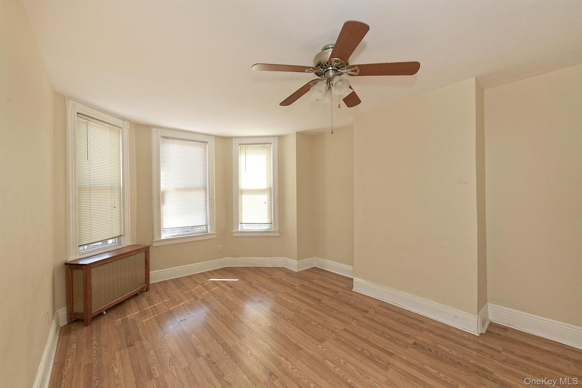 Bedroom featuring radiator heating unit, light wood-style floors, and a ceiling fan