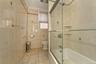 Full bath on 2nd floor featuring enclosed tub / shower combo, tile patterned flooring, radiator heating unit, tile walls, and ornamental molding
