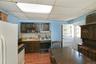 1st Floor Kitchen with backsplash, freestanding refrigerator, light countertops, range with gas cooktop, and dark brown cabinets with entry to yard