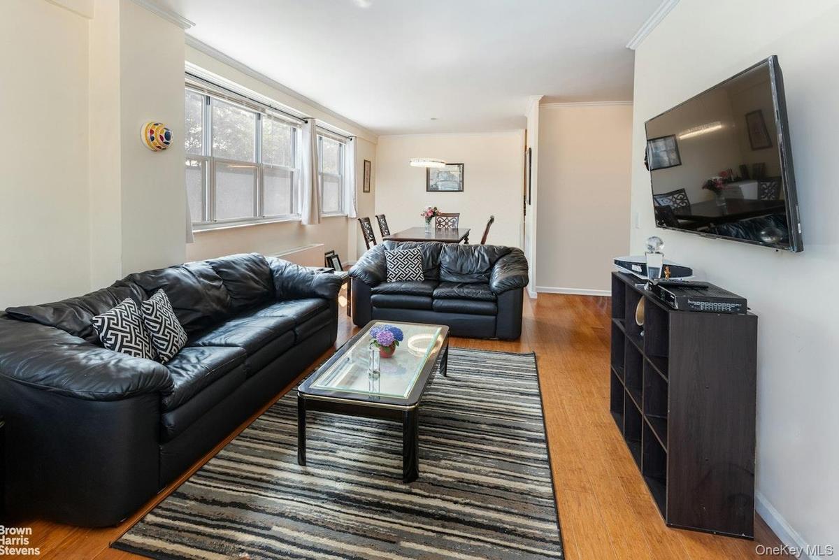 Living area with wood finished floors, baseboards, and crown molding