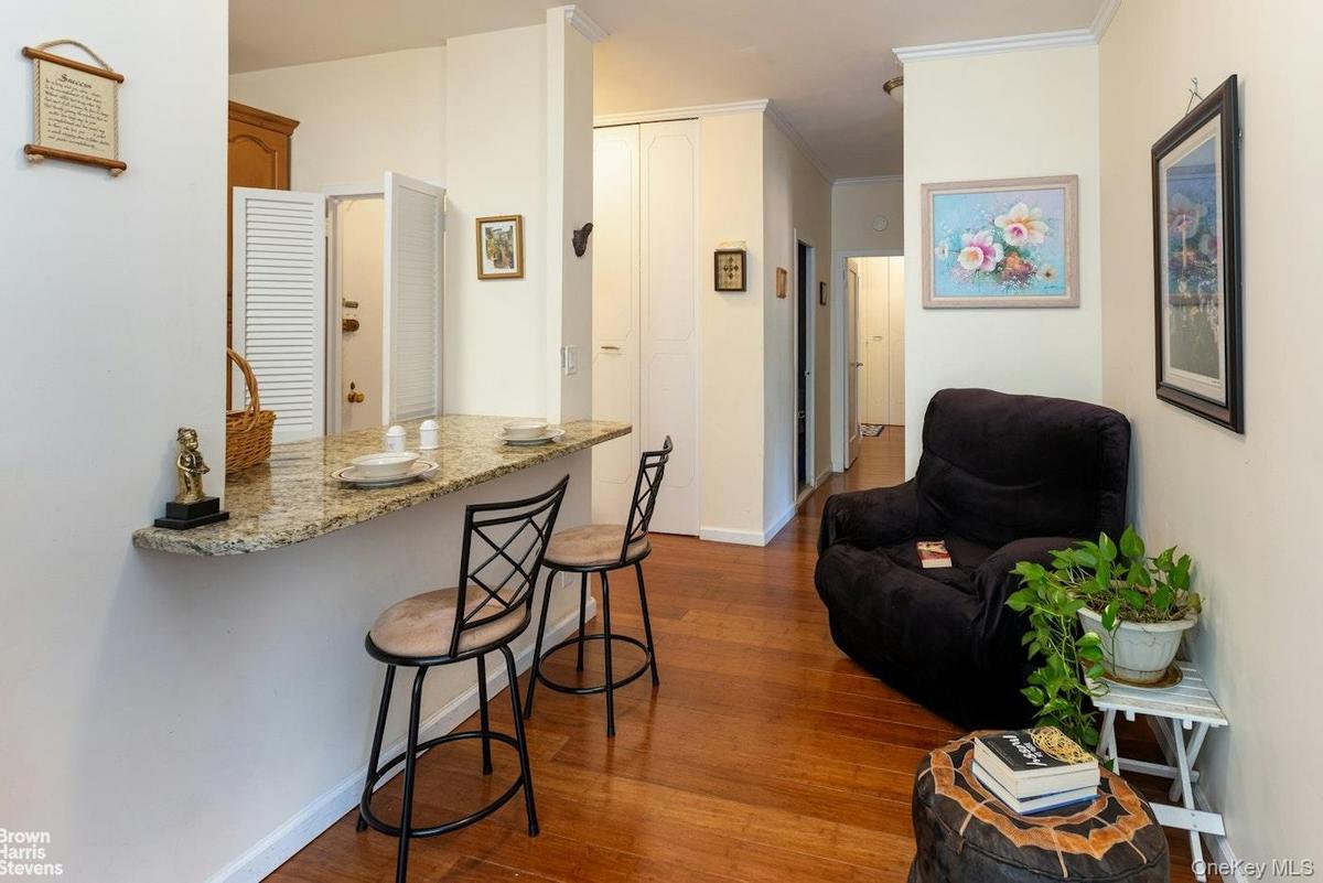 Kitchen featuring a kitchen breakfast bar, dark wood-style floors, ornamental molding, baseboards, and light stone countertops