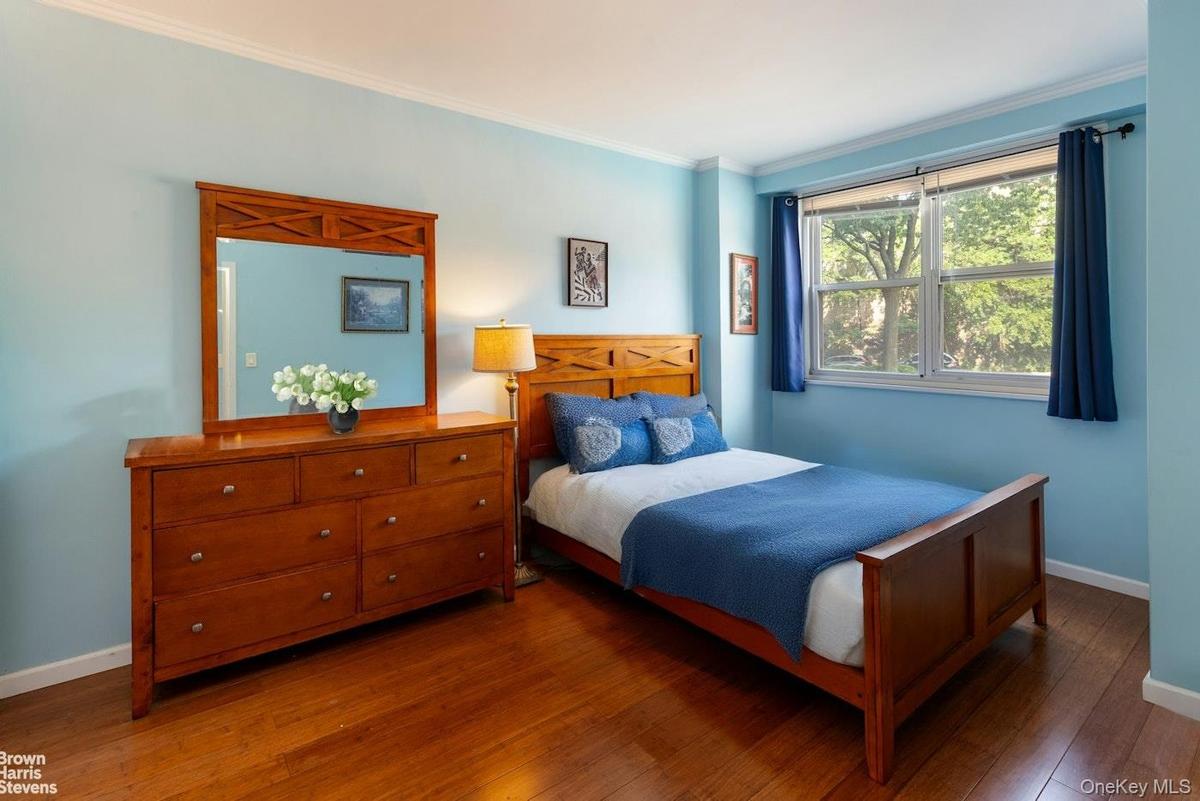 Bedroom featuring wood finished floors, baseboards, and ornamental molding