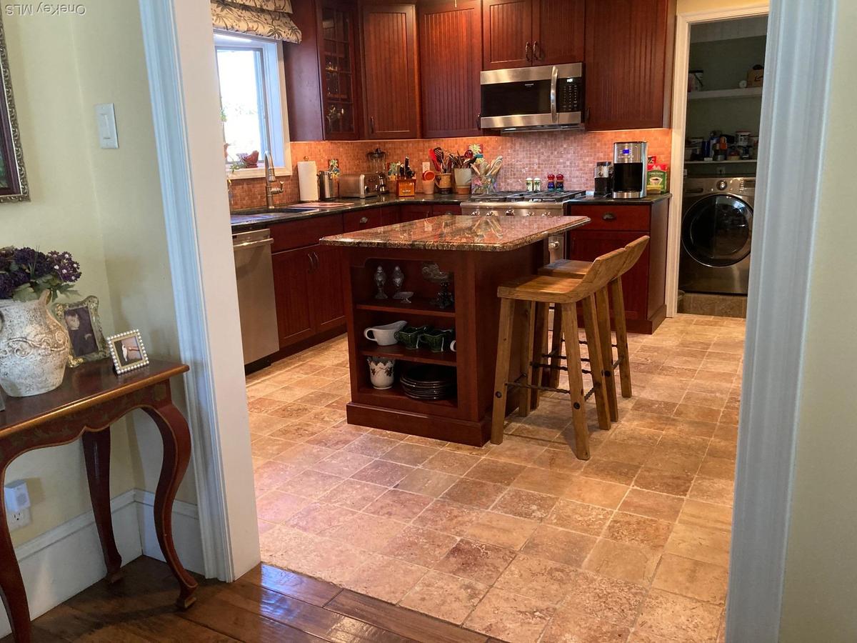 Kitchen with decorative backsplash, dark stone countertops, a kitchen bar, and glass insert cabinets