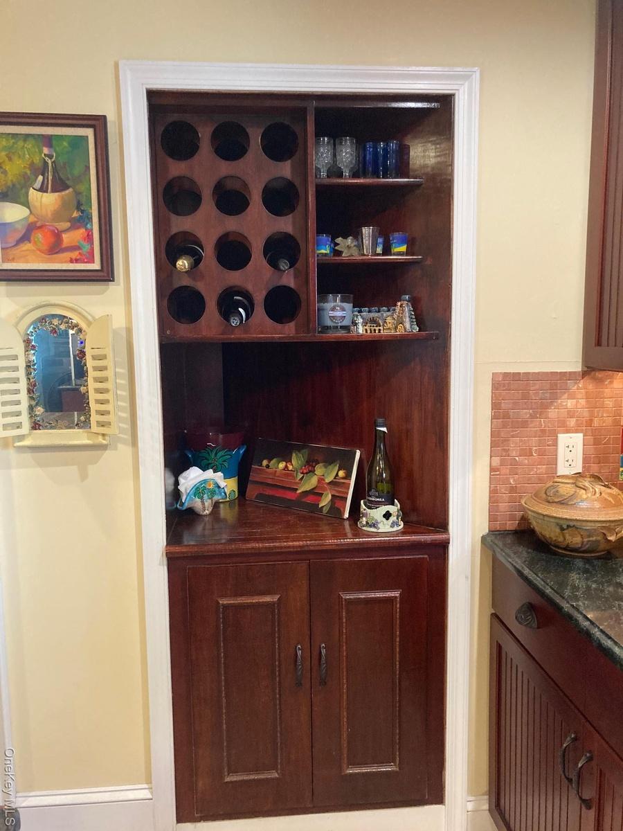 Bar featuring backsplash, dark stone countertops, and dark brown cabinets