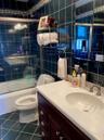Bathroom with dark tile patterned floors, combined bath / shower with glass door, tile walls, and vanity