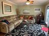 Living room with wood finished floors, crown molding, ceiling fan, and an AC wall unit
