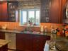Kitchen featuring glass insert cabinets, decorative backsplash, dishwashing machine, stainless steel microwave, and dark stone counters