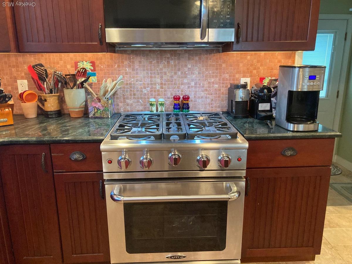 Kitchen featuring tasteful backsplash, stainless steel appliances, and dark stone counters