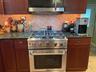Kitchen featuring tasteful backsplash, stainless steel appliances, and dark stone counters