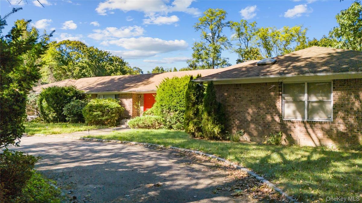 Single story home with brick, driveway, and a front yard