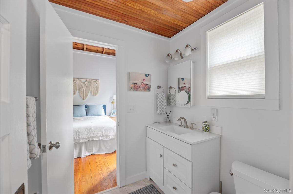 Ensuite bathroom with vanity, wood ceiling, and light tile patterned flooring