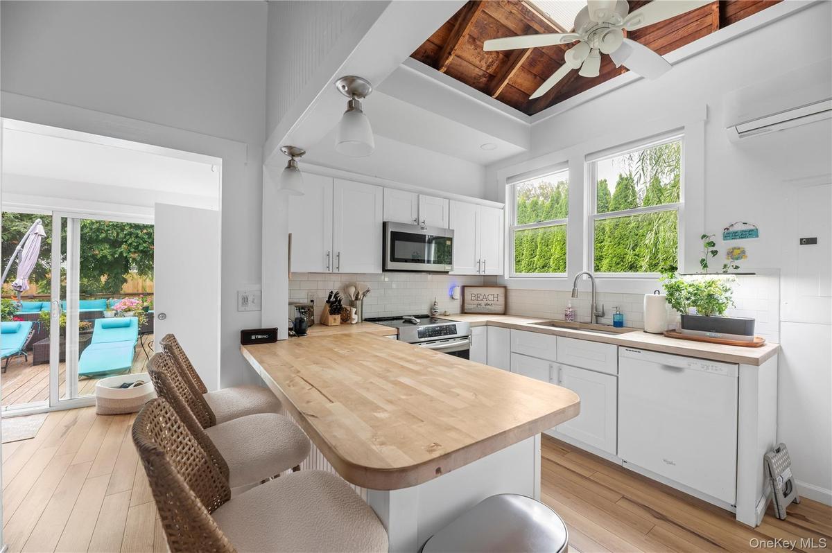 Kitchen with a breakfast bar area, white cabinets, a peninsula, backsplash, and stainless steel appliances