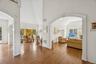 An impressive foyer adorned with oak flooring, vaulted cathedral ceilings, and arched walkways that lead to a sweeping grand stairway.