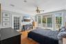 An inviting primary bedroom adorned with wood-finished floors and vaulted ceilings, complete with a ceiling fan and private access to the outdoors.