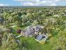 From the rear, the home reveals its inviting charm—complete with a fenced backyard, elegant chimney, and sunroom that seamlessly connects to the mahog
