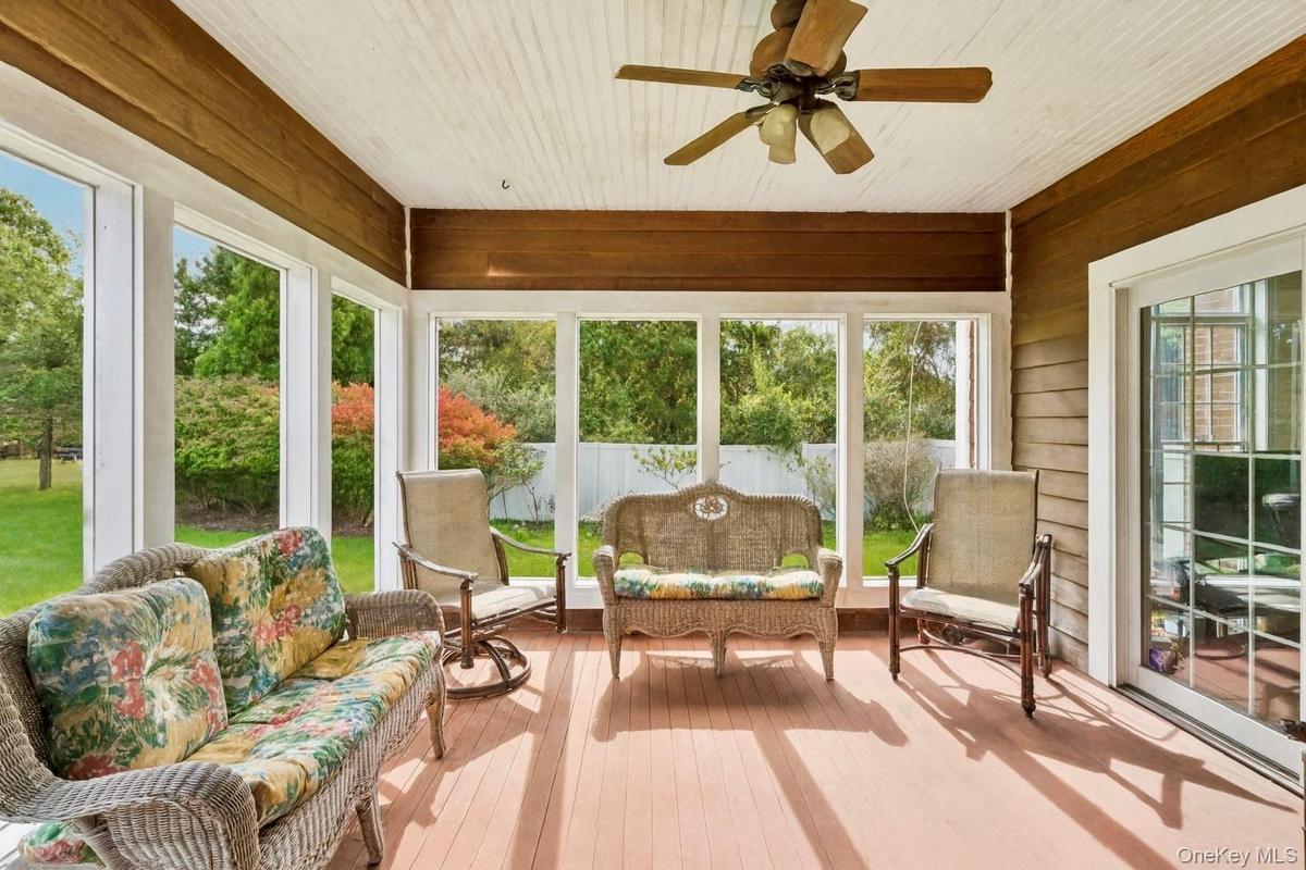 Sunroom featuring a ceiling fan, mahogany wood walls, and a warm, inviting ambiance.