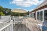 A beautifully crafted mahogany deck designed for outdoor dining and entertaining, accessible through elegant sliding glass doors.