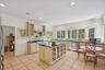 A beautifully appointed kitchen adorned with granite countertops, a central island, custom cabinetry with glass inserts, and an inviting eat-in area.