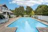 A captivating view reveals the swimming pool, sunlit patio, and spa, all surrounded by a private fenced backyard and complemented by a balcony that ov