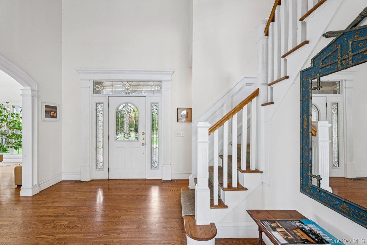 Elegant foyer featuring oak floors, soaring cathedral ceilings, timeless arched walkways, and a beautifully designed stairway.