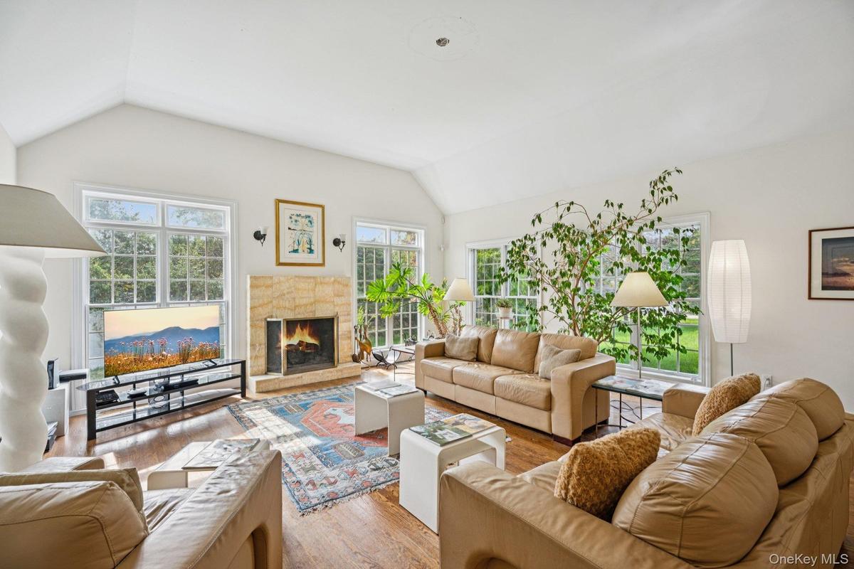 An exquisite living area showcasing vaulted ceilings, rich oak hardwood floors, and a timeless wood-burning fireplace, beautifully encased in floor-to