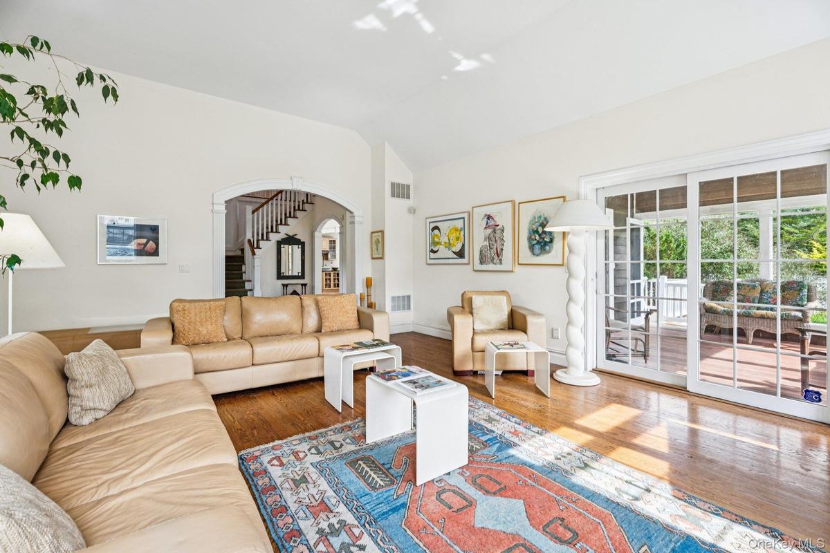 Inviting living area showcasing vaulted ceilings, rich oak hardwood floors, and a charming wood-burning fireplace.