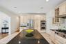 Kitchen featuring granite countertops, a spacious island, glass-inset custom cabinetry, an eat-in dining area, recessed lighting, light-patterned tile