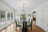 An inviting dining area showcasing graceful arched walkways, warm wood-finished floors, and a stunning chandelier that anchors the space with timeless