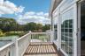The primary bedroom, on the second level, opens to a private balcony offering sweeping views of the property’s expansive yard.