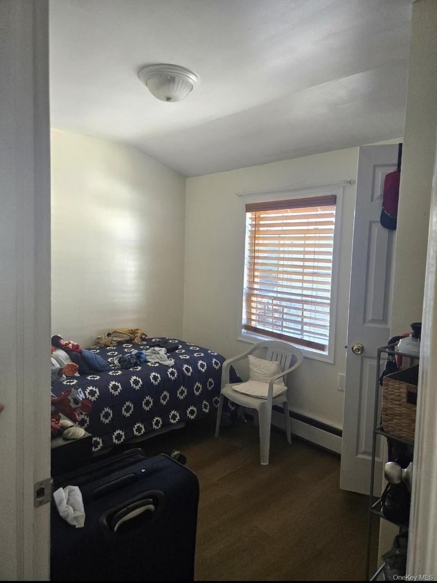 Bedroom with dark wood-style floors and a baseboard radiator