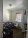 Bedroom with dark wood-style floors and a baseboard radiator