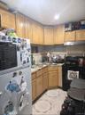 Kitchen featuring freestanding refrigerator, gas stove, light countertops, light tile patterned flooring, and under cabinet range hood