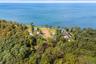 High aerial view showcasing the property’s exceptional proximity to the waterfront, surrounded by mature trees and neighboring properties, with expans